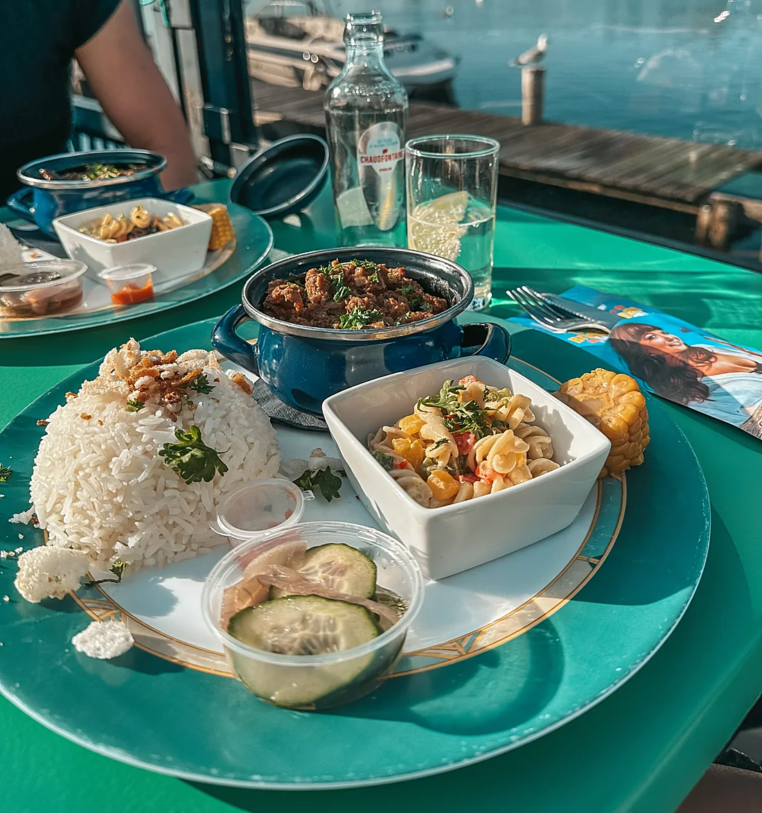 Een bord met nasi, stoofvlees en salade aan de steiger