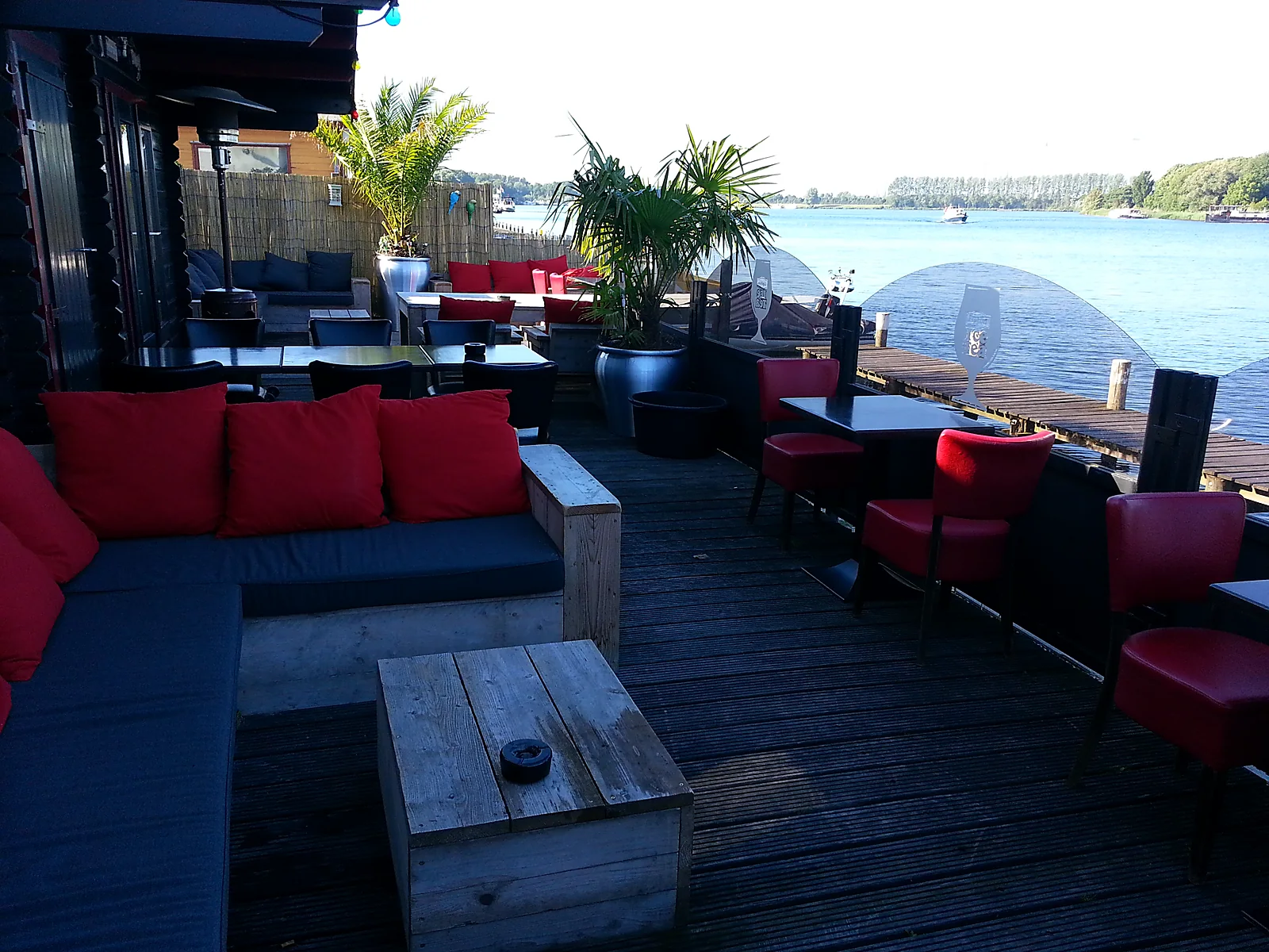 Het terras met rode kussens, loungebanken en het meer