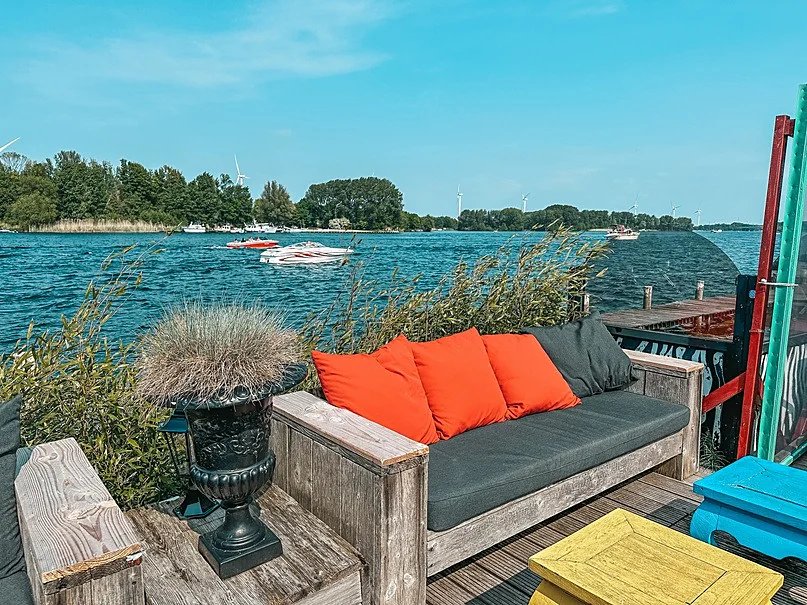 Loungebank met oranje kussens aan het Brielse Meer