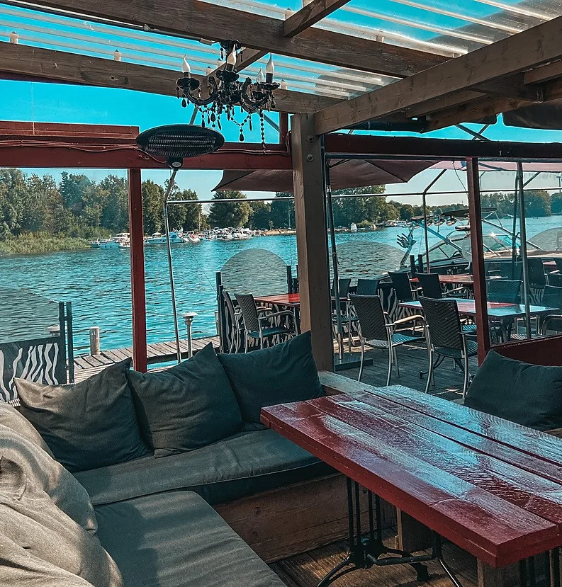 Het overdekte terras met kroonluchter, heaters en uitzicht op het meer