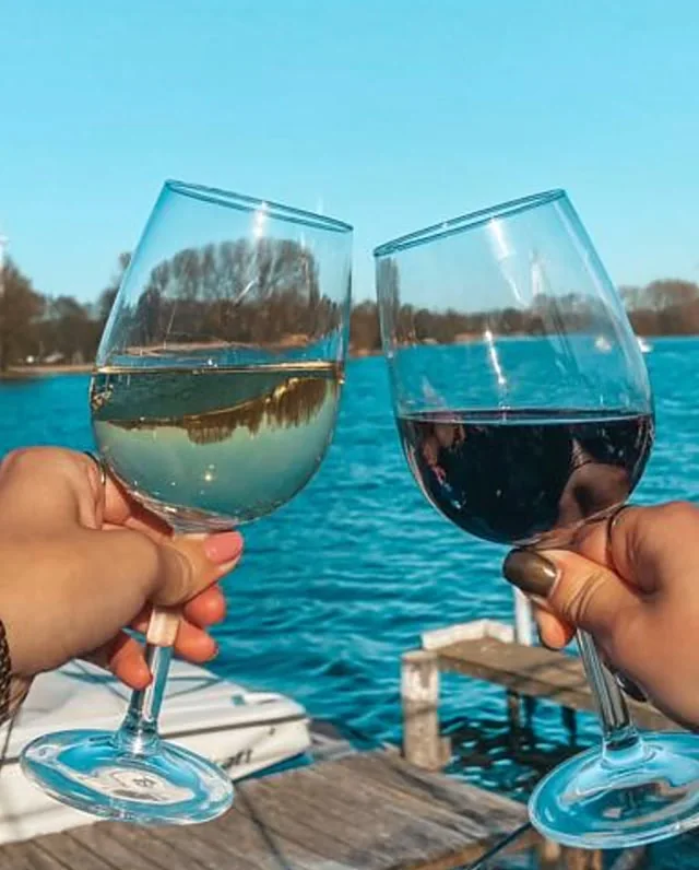 Twee glazen wijn boven het water bij de steiger